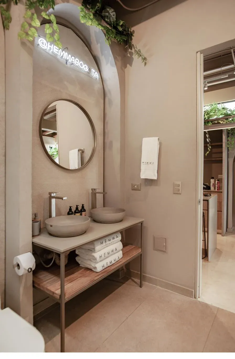 Baño con espejo circular y acabados naturales